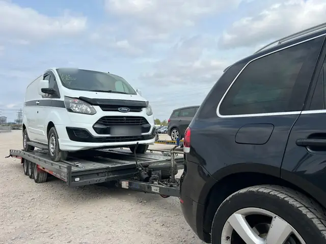 White Ford Transit Custom van loaded on a triple-axle car trailer