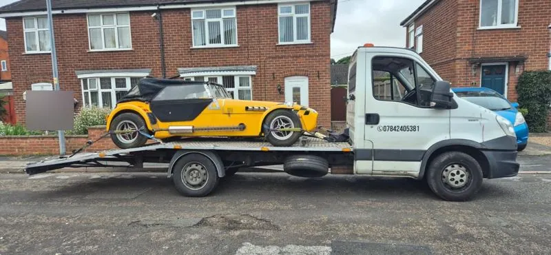 Yellow kit-car roadster on the white truck