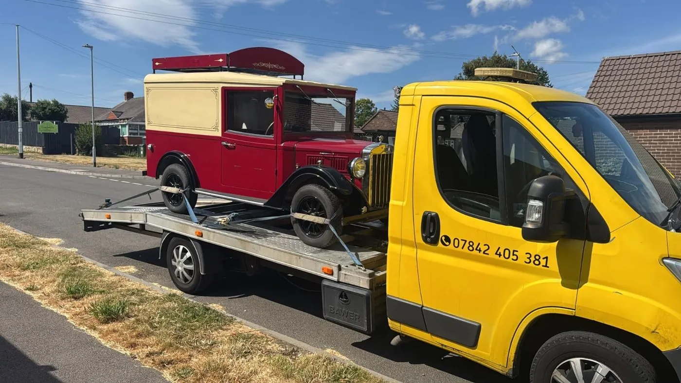 Yellow truck carrying a vintage red and cream van