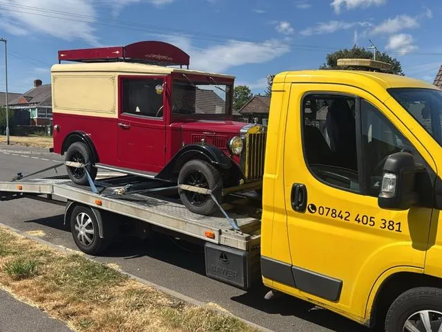 Yellow truck carrying a vintage red and cream van